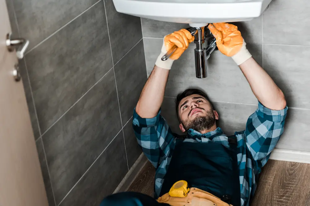 Uomo con guanti che ripara il lavabo in bagno
